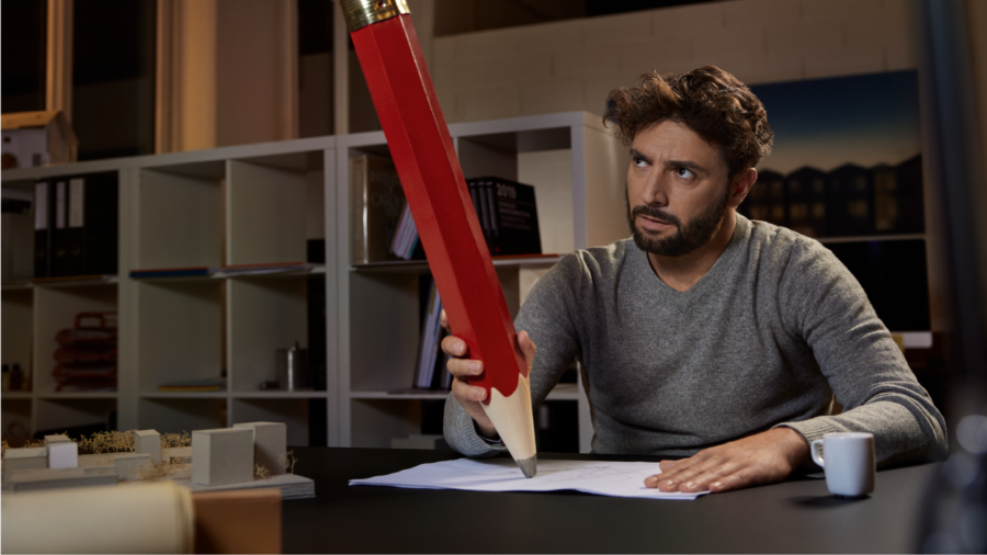 Un homme essaye d'écrire avec un énorme crayon.