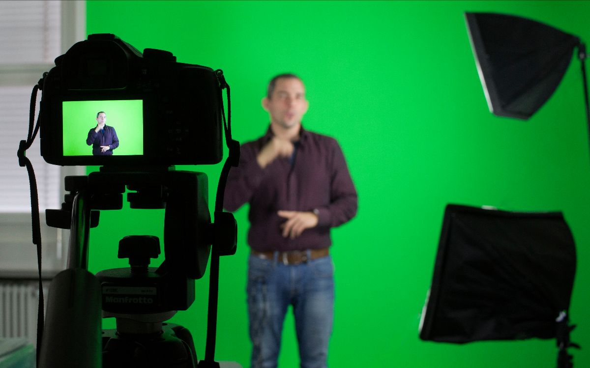 Un homme pratique la langue des signes devant une caméra sur un fond vert