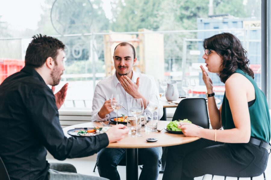 Trois personnes discutent en langue des signes en mangeant au restaurant Vroom