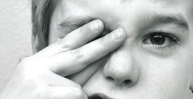 Visage en noir et blanc d'un enfant qui a deux doigts sur l'un de ses yeux