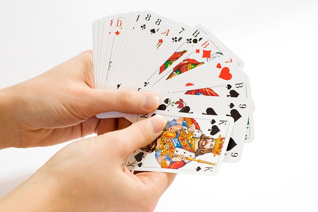 Mains d'une personne tenant un jeu de carte de JASS en éventail.