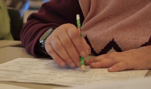 Une personne prend des notes sur un document avec un crayon.